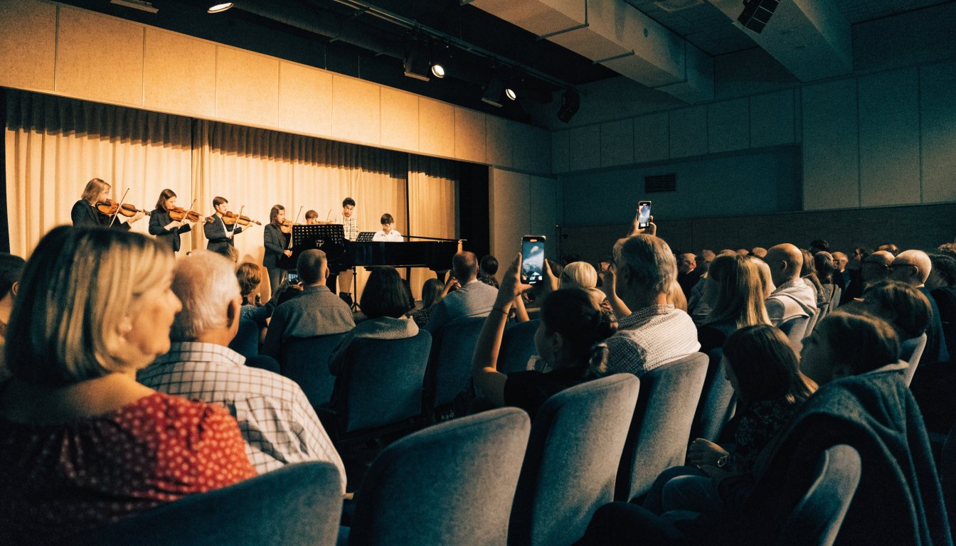 Muestra de fin de año de una academia de música, con familias en el público grabando con sus celulares