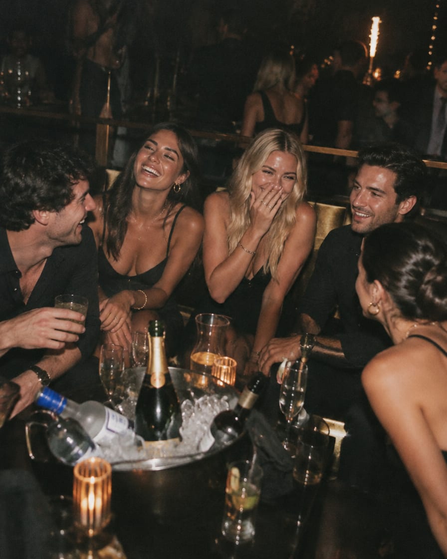 Grupo de amigos riendo en una mesa VIP