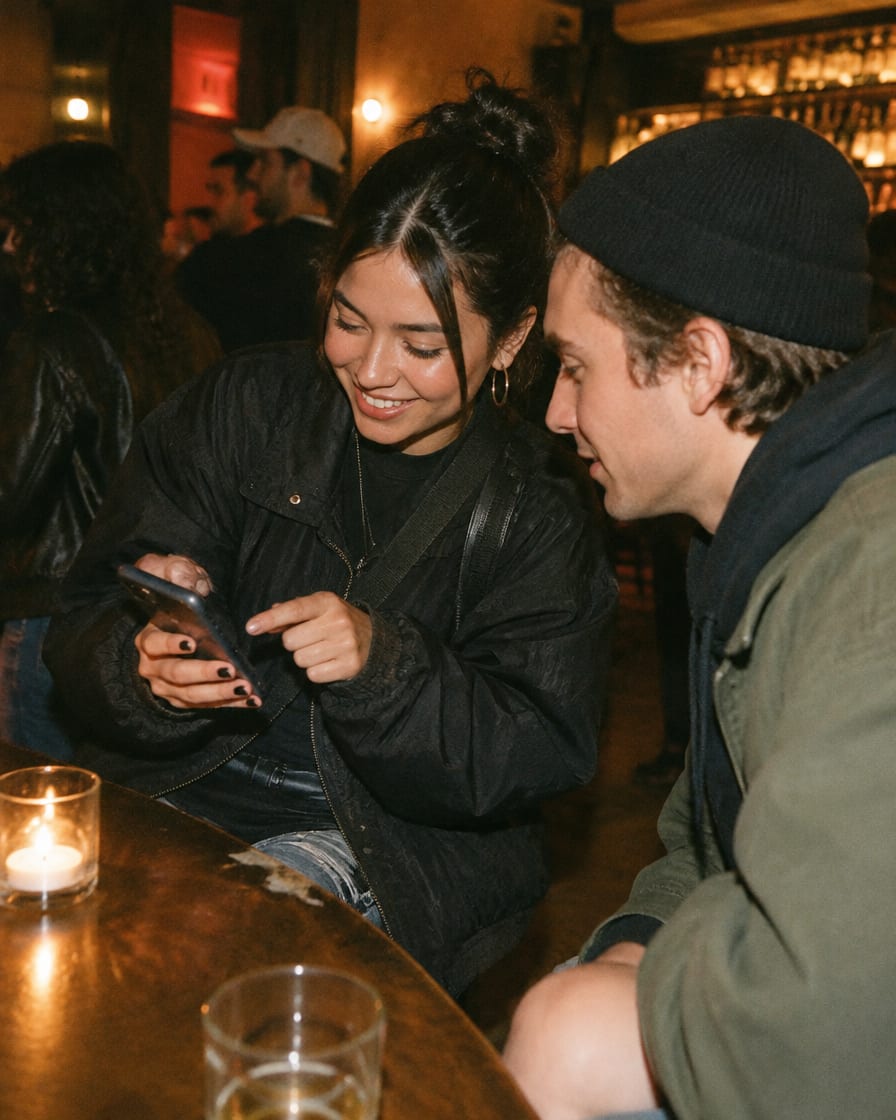 Promotora mostrando su celular a un amigo en una barra