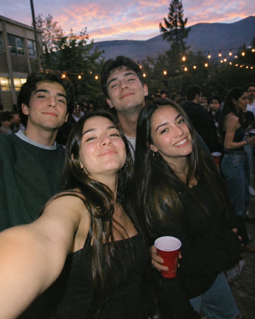 Grupo de amigos sacándose una selfie en una fiesta al aire libre al atardecer