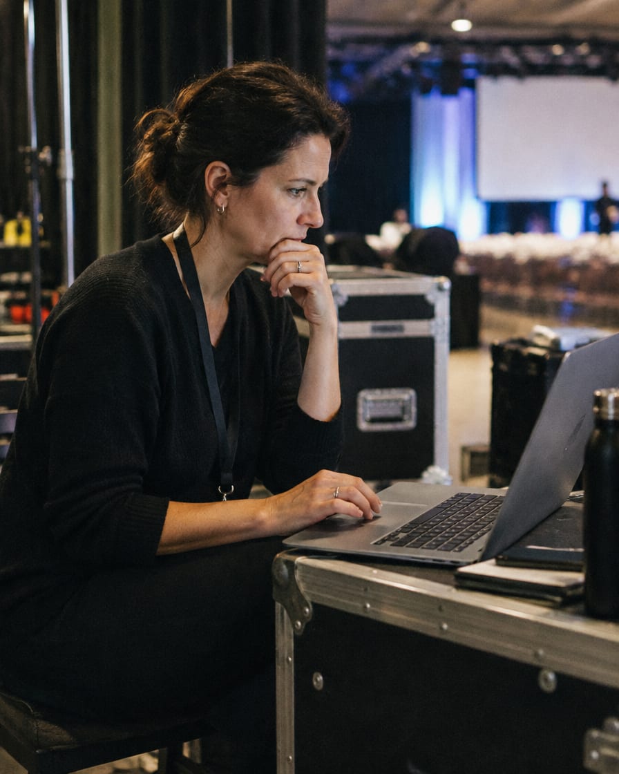 Organizadora revisando el programa en su notebook detrás del escenario